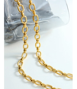 Détail macro du collier à maillons dorés avec texture rainurée sur métal chaud 18 carats
