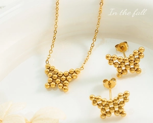 Golden butterfly jewelry set with beaded texture displayed on a white ceramic dish