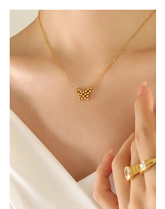 Close-up of a gold butterfly necklace featuring tiny beads on a delicate chain