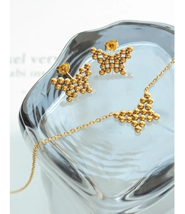 Macro shot of gold butterfly jewelry set featuring beaded texture earrings and necklace
