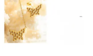 Detail of gold butterfly jewelry set featuring beaded texture on white coral background