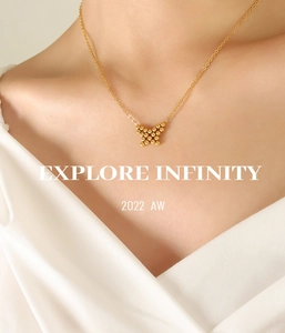 Close-up of gold butterfly pendant necklace with bead details worn by a model
