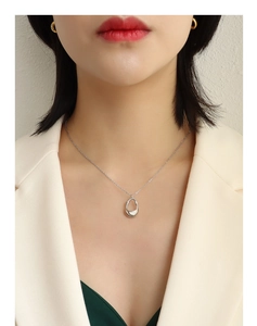 Silver necklace featuring abstract drop pendant on model wearing beige blazer