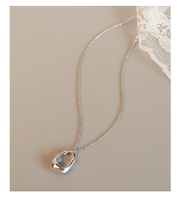 Detail of silver hollow irregular pendant on thin chain with polished metallic finish