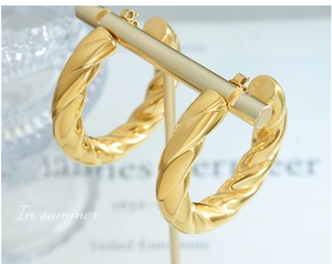 Macro view of gold twisted hoop earrings with a high-gloss spiral texture and sleek finish