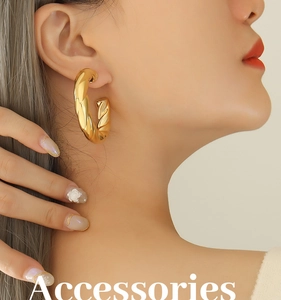 Close-up of a large gold hollow C-shaped earring with twisted croissant texture