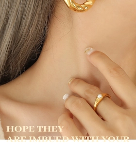 Detail of gold twisted hoop earring and pearl ring on model showing texture and finish