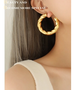Close-up of chunky gold-plated hollow C-shape twisted hoop earrings with spiral texture