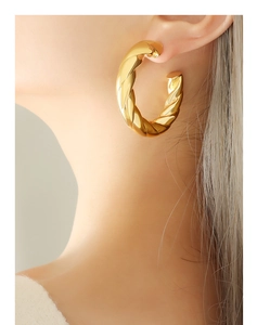 Close-up of golden twisted rope hoop earrings worn by a model in French vintage style