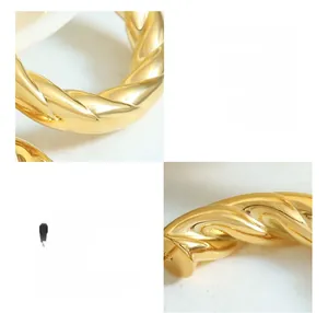 Detailed macro view of gold-plated titanium hollow C-shaped earrings with twisted texture