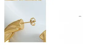 Close-up of golden hollow C-shaped earring showing needle and butterfly back detail