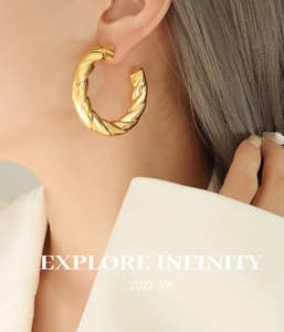 Close-up of model wearing chunky twisted C-shaped gold hollow hoop earrings