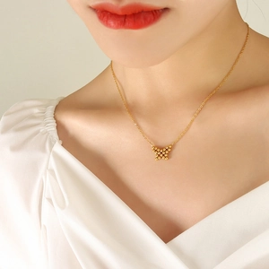 Minimalist gold butterfly necklace with polished bead design on a model's neck
