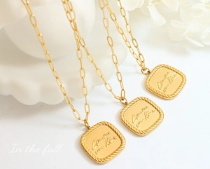 Detail of paperclip chain necklace with gold square pendant and French engraving