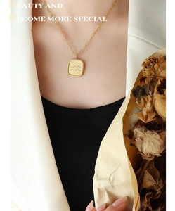 Close-up of 18K gold plated square letter pendant necklace on paperclip chain