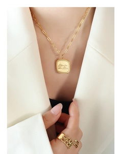 Close-up of 18K gold plated necklace and ring with engraved square pendant details