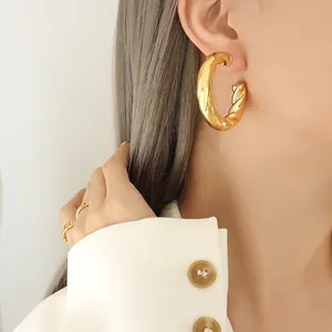 French design hollow twisted gold hoop earrings worn by a model for a stylish look
