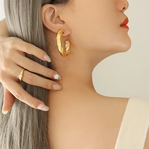 French design hollow C-shaped chunky gold twisted hoop earrings worn by a model
