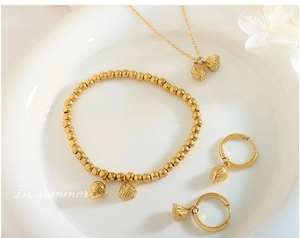 Detail view of gold lotus pod jewelry set including beaded bracelet and chain necklace