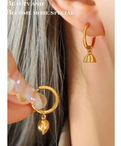 Close-up of golden lotus flower earrings in 18K plated steel worn by a model