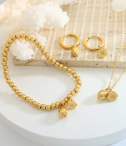 Detailed set of gold lotus and plum blossom jewelry on a textured display stand