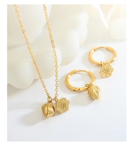 Macro detail of gold lotus flower pendant and earrings set on a minimalist white background