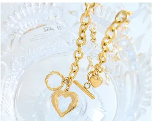 Macro shot of gold heart pendant with feather texture and OT toggle clasp detail