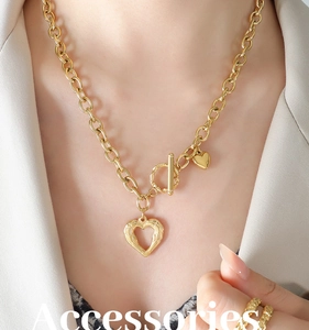 Detailed close-up of golden OT clasp necklace with double heart pendants on a model