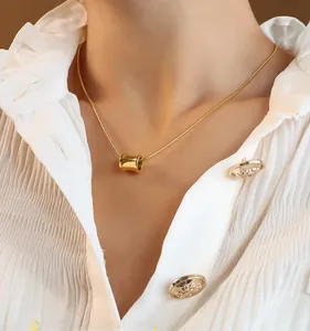 Detail of 18K gold-plated cylinder pendant and snake chain on a white shirt