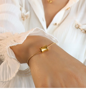 Detail view of 18K gold plated snake chain bracelet worn on wrist with chiffon cuff