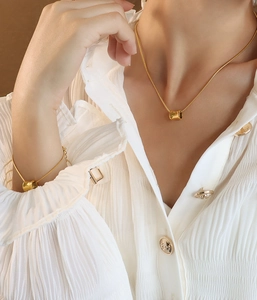 Detailed shot of gold snake chain necklace and bracelet set on a white blouse