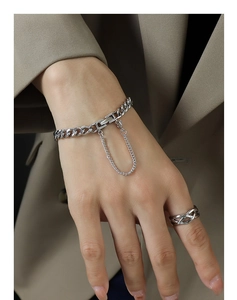 Detalle de pulsera de cadena cubana plateada y anillo calado en la muñeca del modelo