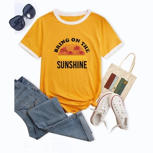 Flat lay of yellow t-shirt with sunshine graphic, denim jeans and casual accessories