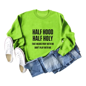 Gros plan du sweat-shirt vert néon avec le détail du texte noir Half Hood Half Holy
