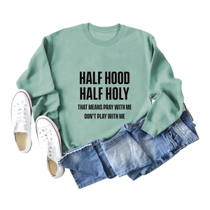 Sweat vert menthe avec slogan Half Hood Half Holy et jean posé à plat pour un look casual