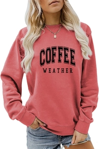 Detail of salmon pink crewneck sweatshirt featuring black COFFEE WEATHER text print