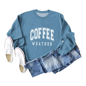 Detailed view of blue crewneck sweatshirt with white COFFEE WEATHER print layout