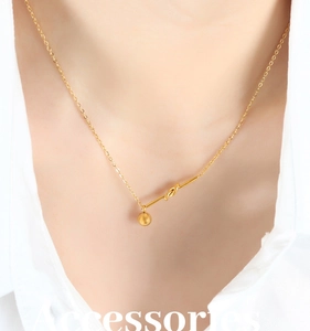 Close-up of golden knot pendant necklace with dangling steel ball on a female model