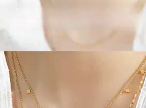 Close-up of a double-layered gold necklace with geometric diamond charms on a model