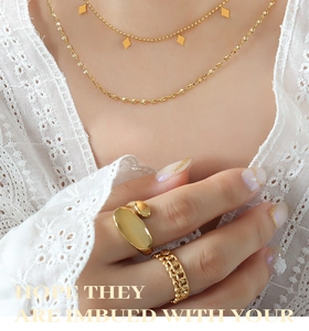 Detail of layered gold titanium necklaces with diamond pendants and textured rings