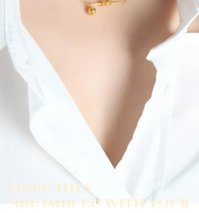 Macro view of gold-tone knot necklace with polished bead pendant on female model