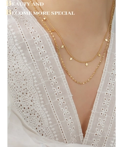 Macro detail of gold layered necklace featuring delicate geometric rhombus charms on model
