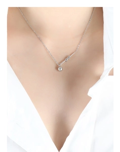 Close-up of silver knot pendant necklace with ball fringe worn on a white shirt