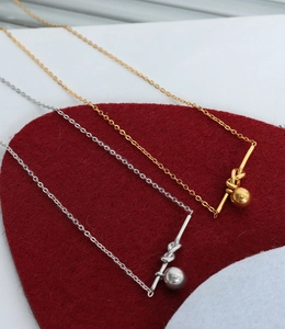 Close-up of geometric knotted bar pendants with small beads on gold and silver necklaces