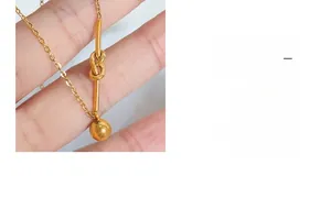 Detail of gold knot necklace with round bead pendant showing polished metallic texture