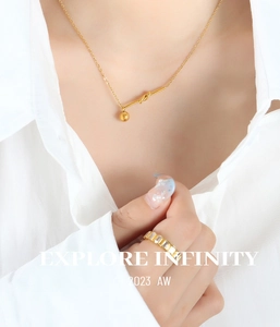 Macro detail of gold-plated knot pendant necklace with small ball charm on a model