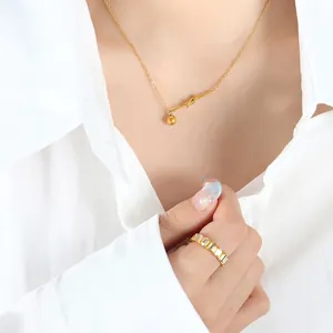 Minimalist gold knot pendant necklace and baguette cut eternity ring on a model