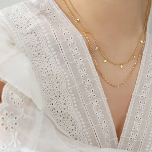 Double-layered gold titanium necklace with geometric diamond charms on beaded and rope chains
