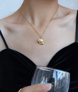 Detailansicht der 18k Gold Lotus-Halskette mit Perle an einem Model im schwarzen Samtkleid