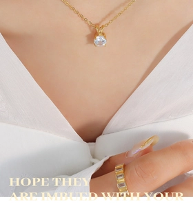 Close-up of 18K gold necklace with zircon pendant and matching gemstone ring on model